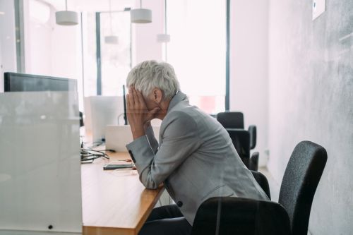 Stressed older woman working in an office. Age Discrimination in Employment Concept.