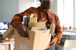 Close up of senior man holding box with personal items leaving office workplace for retirement copy space