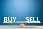 The words buy and sell are balanced on a seesaw.